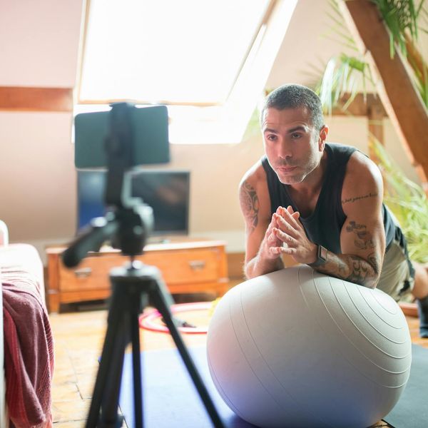 A person gently stretching indoors, surrounded by plants.